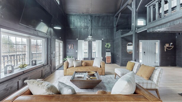 A spacious room with large windows, a wooden coffee table, and a sofa set. - Seneca Lake Barndominium Retreat (Quaker City)