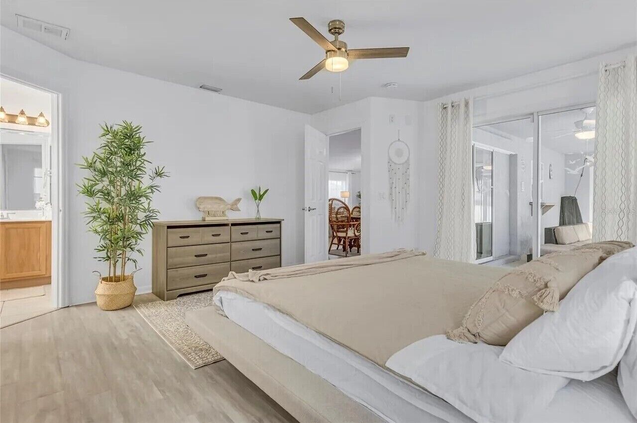Une chambre à coucher avec un lit, un ventilateur de plafond, une commode, une plante en pot et un attrape-rêves.