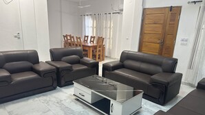 A modern living room with two sofas, a glass coffee table, and a dining area with a wooden table and chairs. - 3-bedroom house in marvelous Baguida Lomé with cool AC (Lomé)