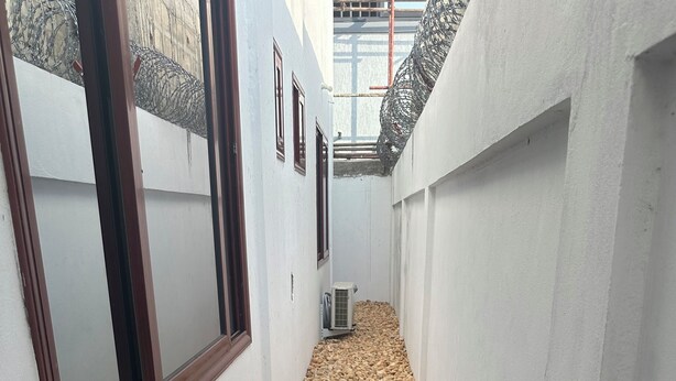 A narrow corridor with white walls, a gravel path, and air conditioning units. - 3-bedroom house in marvelous Baguida Lomé with cool AC (Lomé)