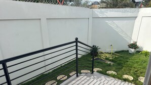 A balcony with a metal railing, a tiled floor, and a grassy area with stepping stones. - 3-bedroom house in marvelous Baguida Lomé with cool AC (Lomé)