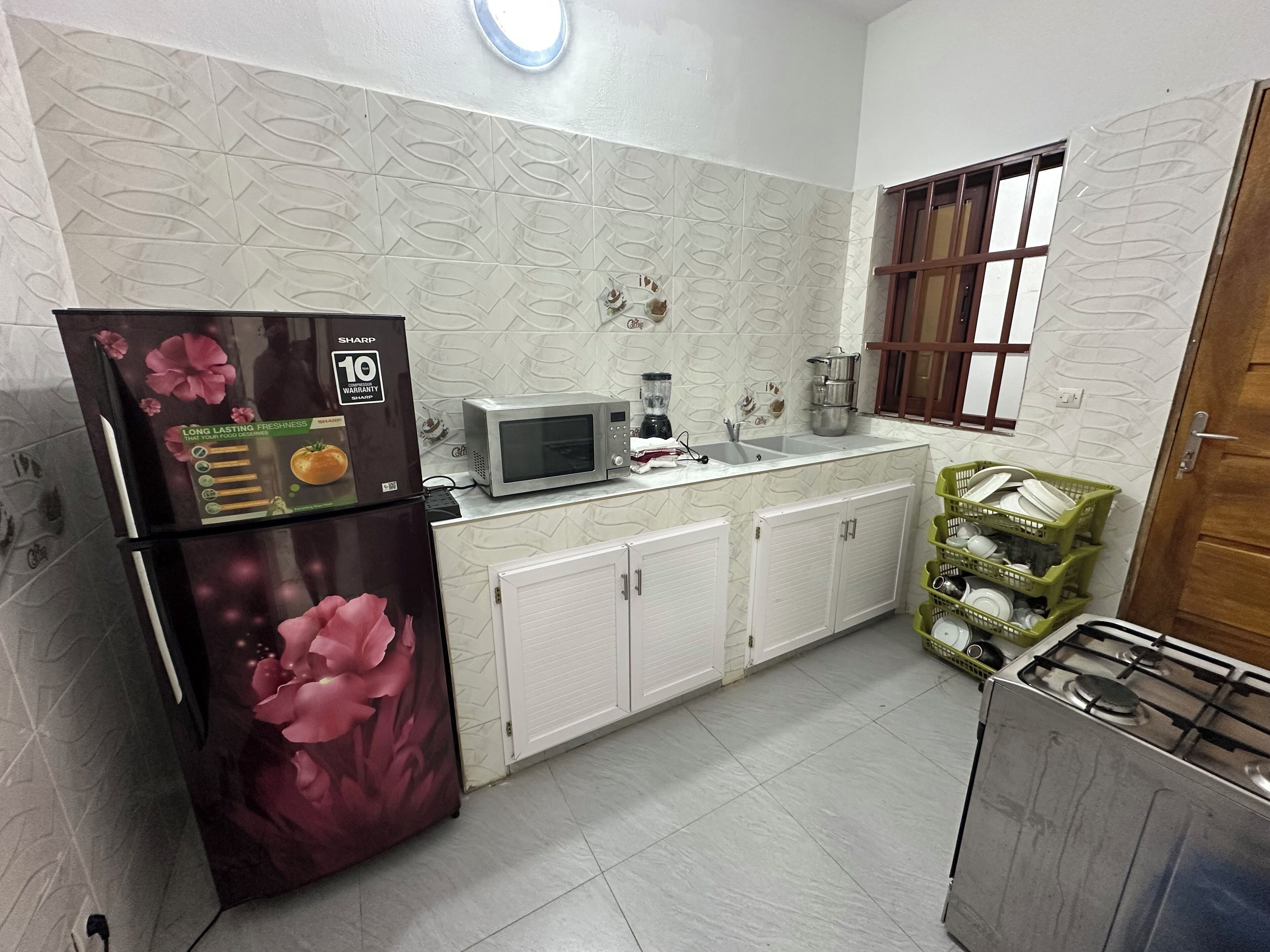 A kitchen with a refrigerator, microwave, sink, cabinets, and a stove.