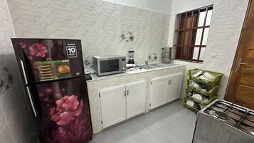 A kitchen with a refrigerator, microwave, sink, cabinets, and a stove.