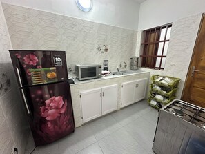 A kitchen with a refrigerator, microwave, sink, cabinets, and a stove.