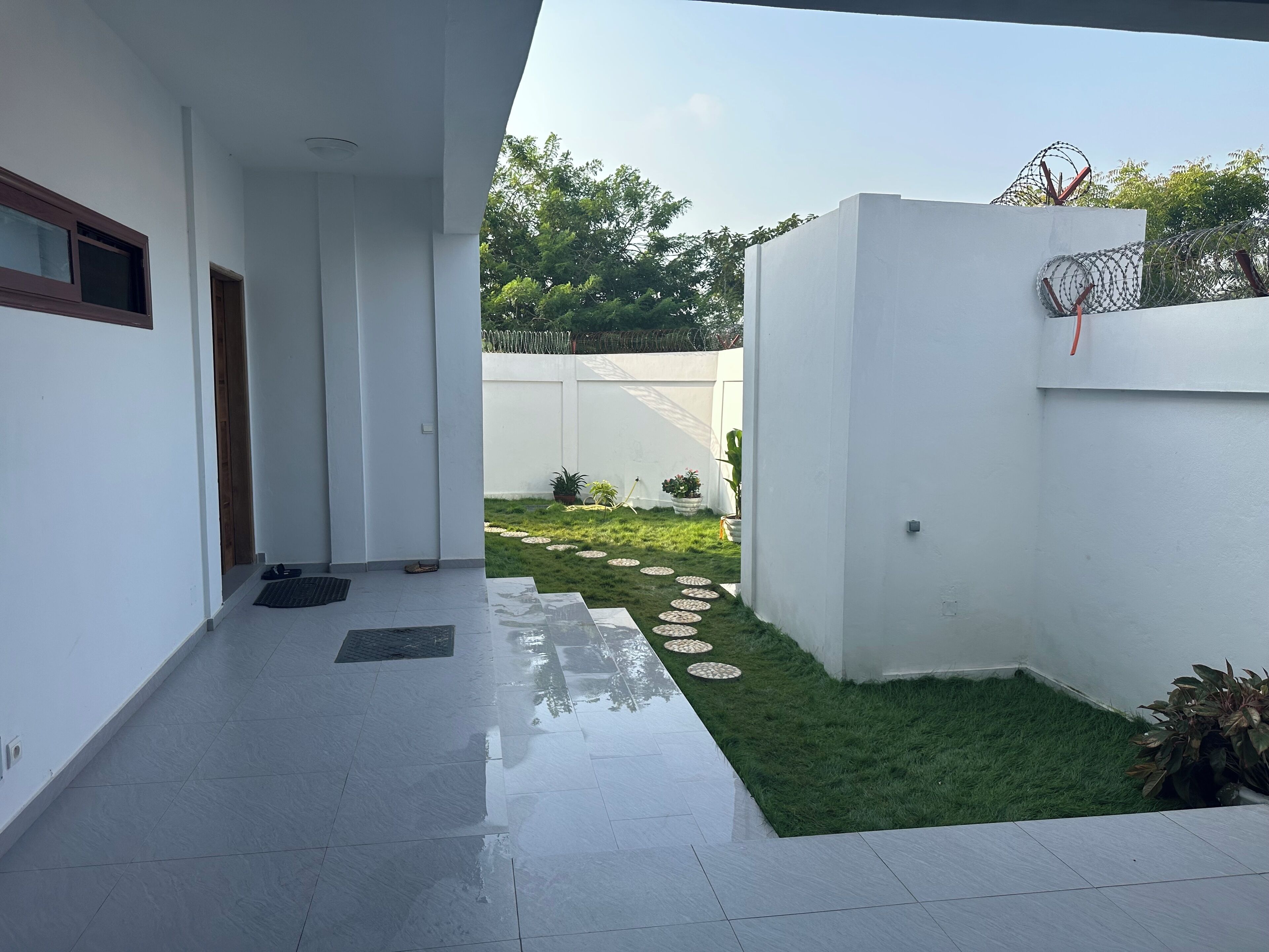 A modern building with a clean, white exterior and a small, well-maintained garden area with stepping stones and potted plants.