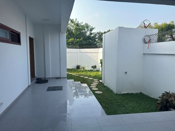 A modern building with a clean, white exterior and a small, well-maintained garden area with stepping stones and potted plants.