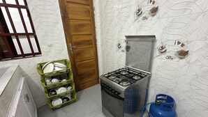 A small kitchen with a gas stove, a blue gas cylinder, and a green dish rack with dishes. - 3-bedroom house in marvelous Baguida Lomé with cool AC (Lomé)