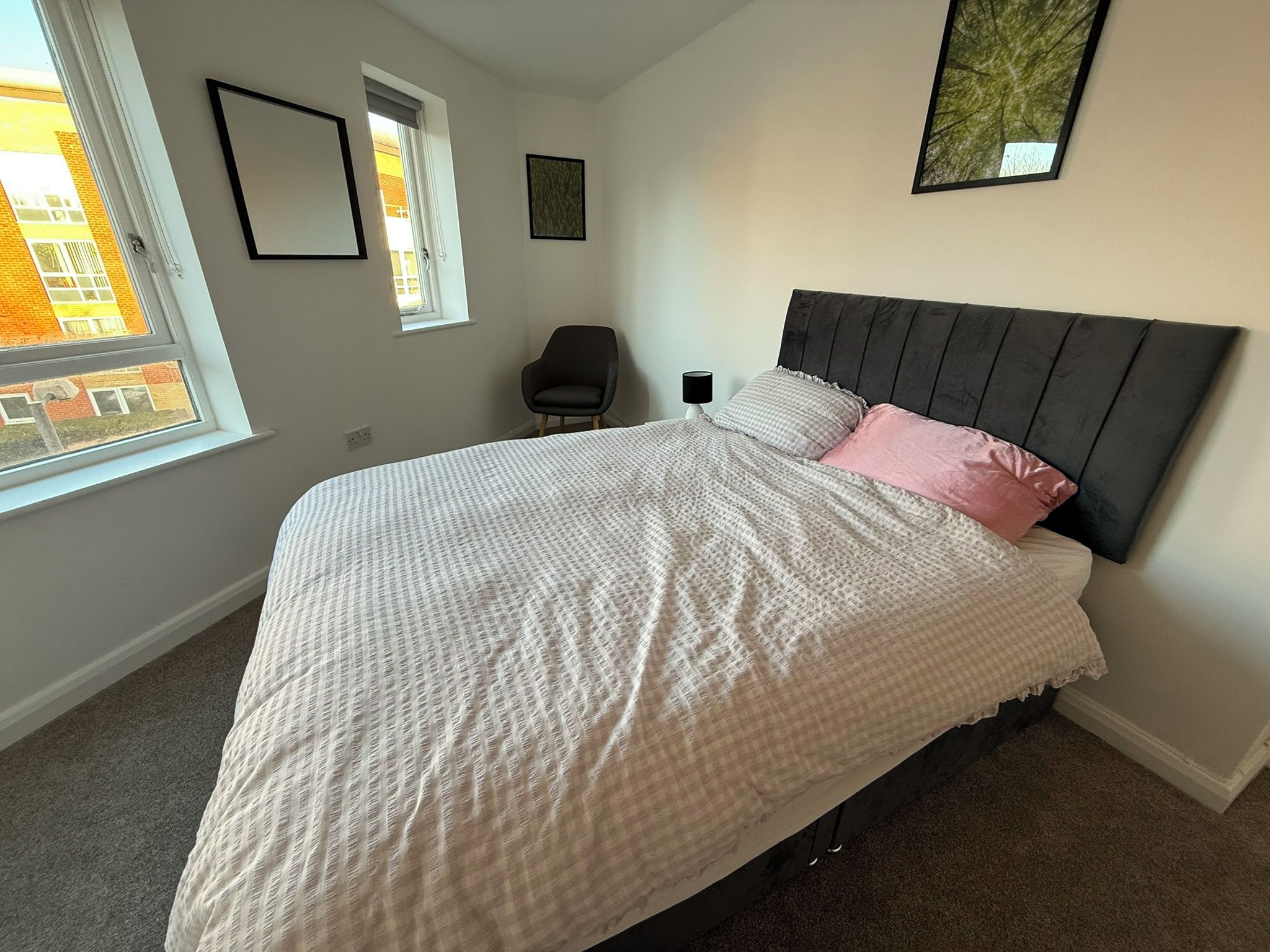 Ein Schlafzimmer mit einem Bett, einem Sessel, einem Fenster und einem Bild an der Wand.