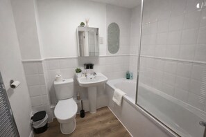 A bathroom with a toilet, sink, and bathtub. - Modern 2BDR Flat in East London Near Beckton DLR (Greater London)