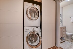 A compact laundry room with two front-loading washing machines and a small bathroom with a toilet and cabinet. - Updated Apt | Walking Distance to Ski Shuttle and Dining! (Avon)