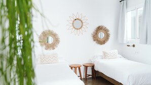 Una camera da letto dal design minimalista con due letti, uno specchio rotondo e un tavolino.