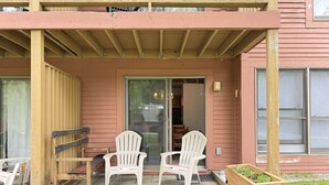 Une véranda avec deux fauteuils Adirondack, un banc en bois et un parterre surélevé.