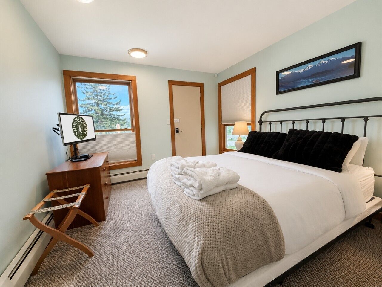 A bedroom with a bed, a desk, a chair, a window, and a picture on the wall.