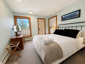 Une chambre à coucher avec un lit, un bureau, une chaise, une fenêtre et un tableau au mur.