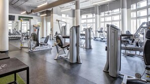 Un gimnasio con diversas máquinas de ejercicio, bancos de pesas y mancuernas.