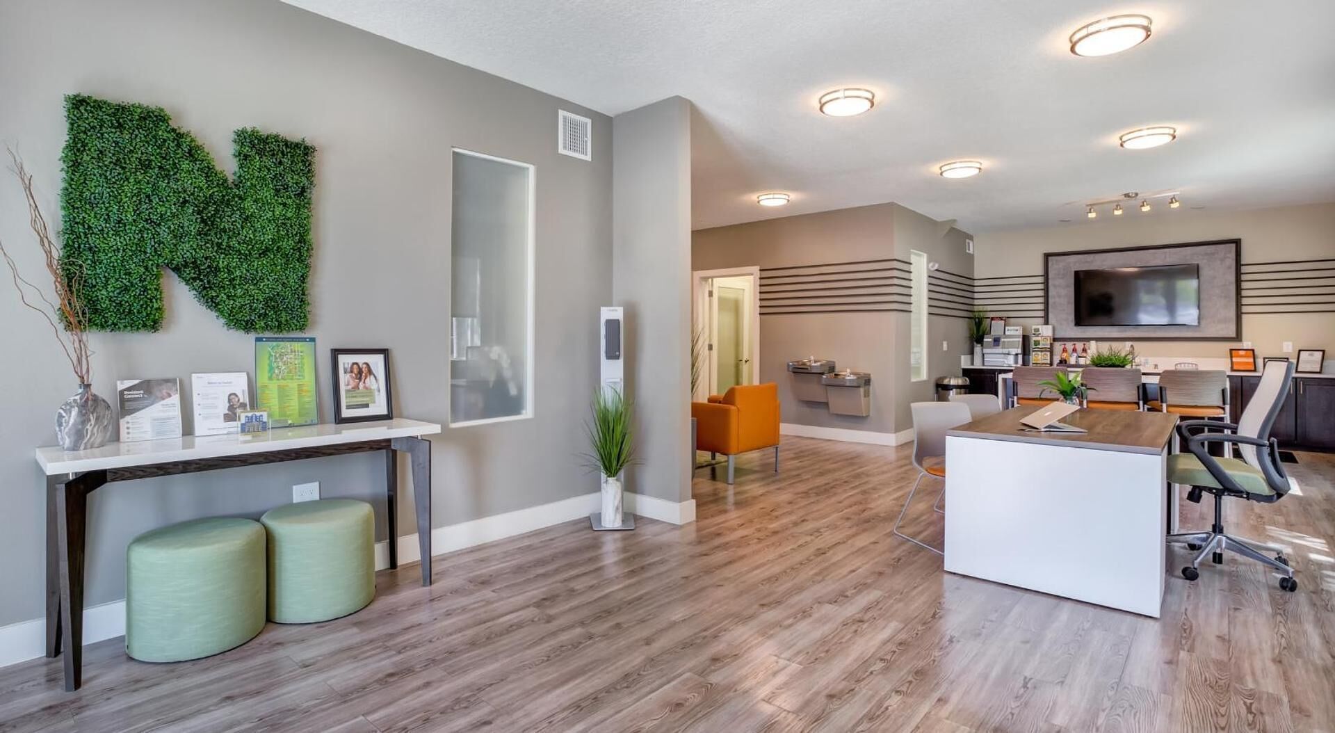 A modern interior with a reception desk, seating area, and a large flat-screen TV mounted on the wall.