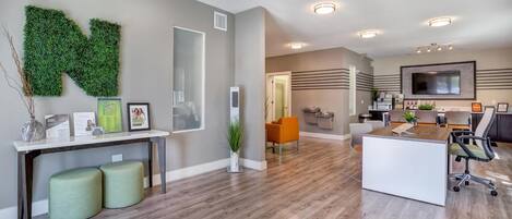 A modern interior with a reception desk, seating area, and a large flat-screen TV mounted on the wall.