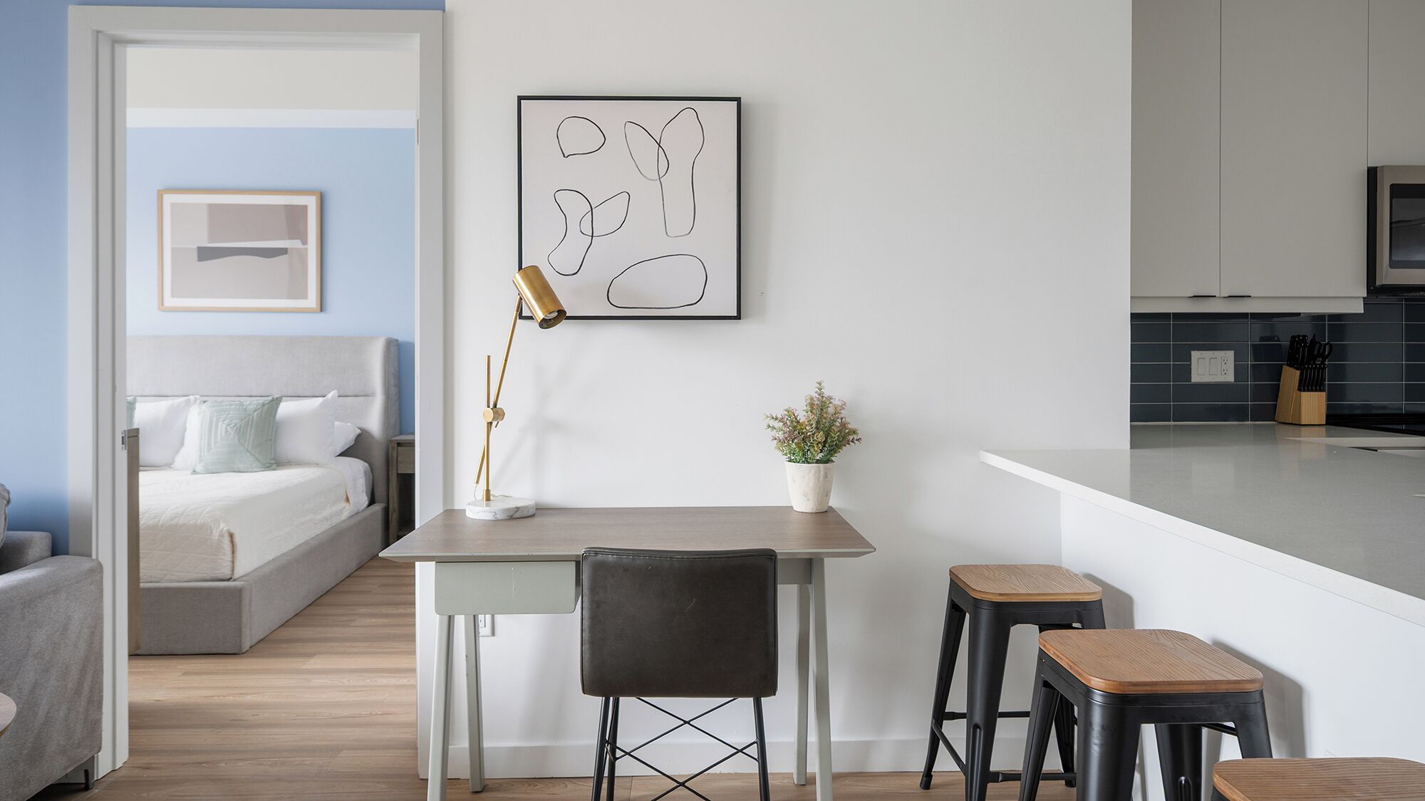 En moderne lejlighed med spiseområde, køkken samt et soveværelse med seng og natbord.