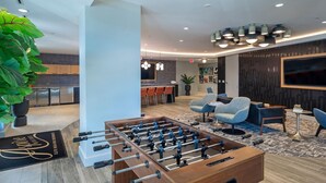 Eine moderne Lobby mit Kicker, Sitzgelegenheiten und einer Bar.