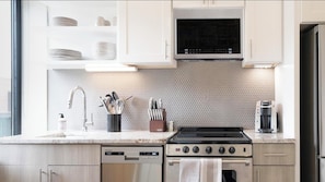 A modern kitchen with white cabinets, a stainless steel stove, a microwave, and a dishwasher. - Landing Apartments Near Albany Medical College (Albany)