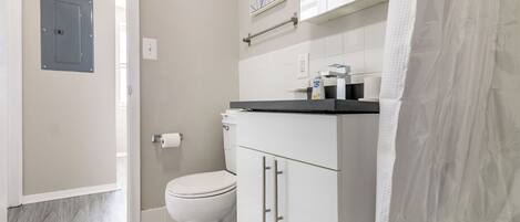 Een badkamer met toilet, wastafel en douchegordijn.