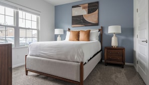 Una camera da letto con un letto, due comodini, un tavolino e un quadro appeso al muro.