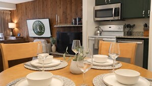 Een eethoek met een houten tafel voor vier personen, omringd door groene kastjes en een magnetron.