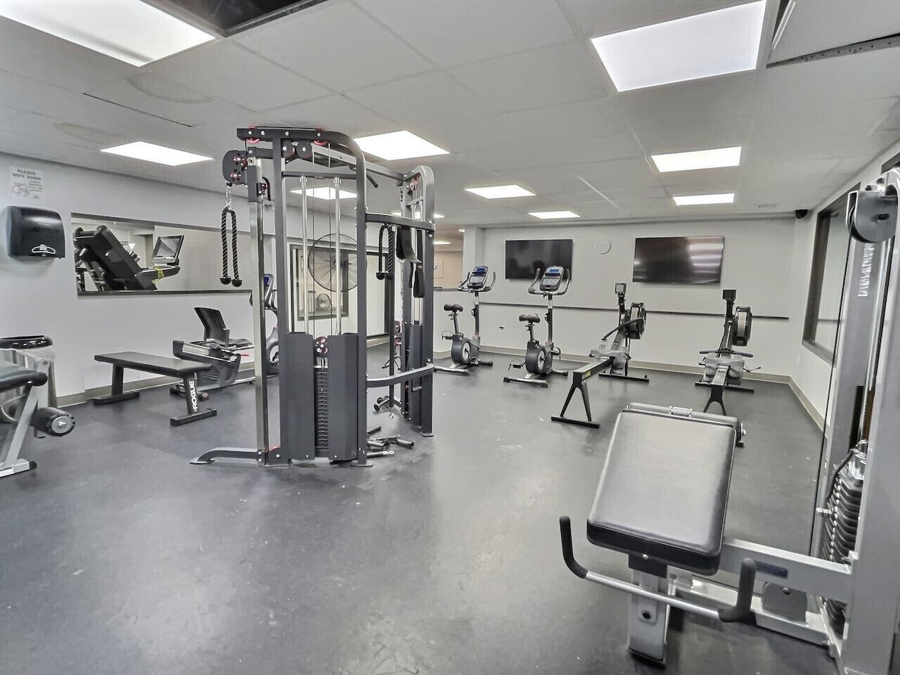 A gym with various exercise equipment, including a squat rack, treadmills, and weight machines.