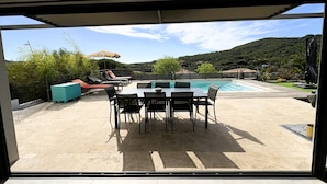 A poolside area with a table and chairs, a covered seating area, and a view of a mountainous landscape. - Villa 4 bedrooms heated pool Sainte Maxime (Sainte-Maxime)