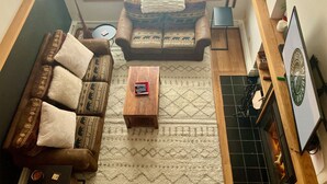 A cozy living room with a sofa, a coffee table, and a fireplace. - Hilltopper Haus- Pool, hot tub, Private Sauna (Killington)
