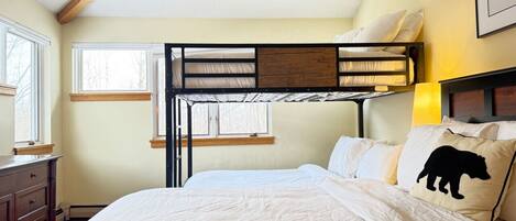 Dormitorio con literas, cabecera de madera, cómoda y ventana.
