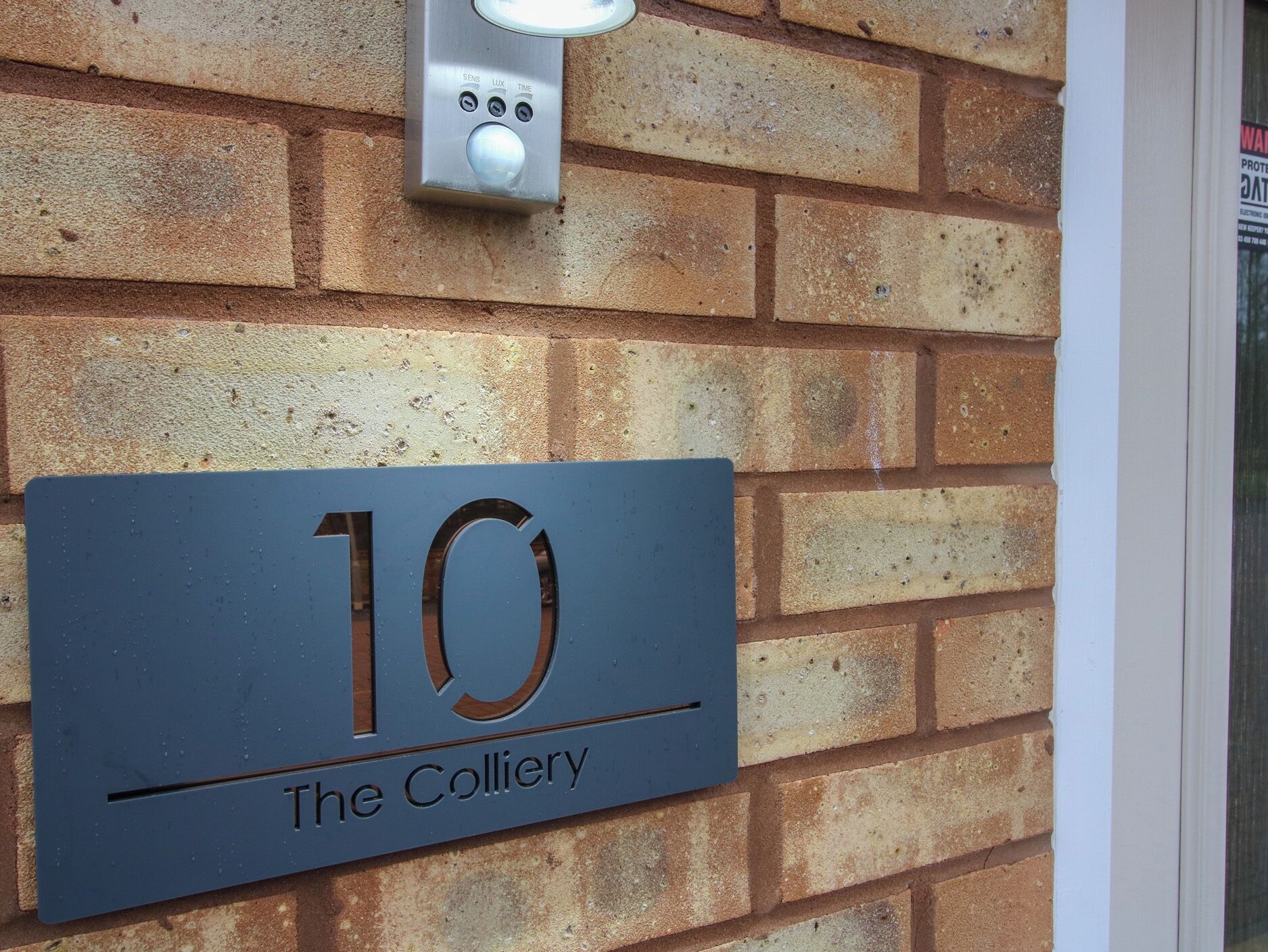 A metal sign with the number 10 and the words "The Colliery" on a brick wall.