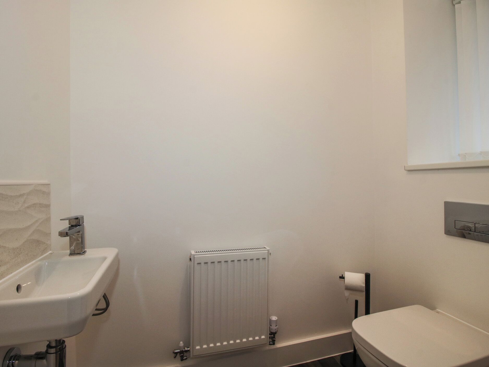 A bathroom with a white sink, toilet, and radiator.