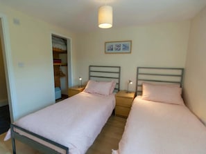 Een slaapkamer met twee bedden, een kast en een plafondlamp.