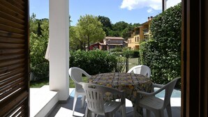 A patio with a table and chairs, a view of a residential area, and a white column structure. - N305 – Numana, comfortable three-room apartment with garden (Numana)