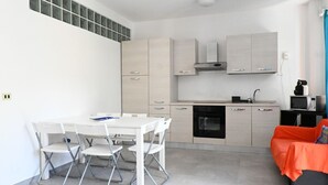 A compact kitchen with a dining area, a microwave, and a black oven. - N305 – Numana, comfortable three-room apartment with garden (Numana)