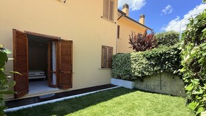 A house with a well-maintained lawn, wooden shutters on the windows, and a small entryway. - N305 – Numana, comfortable three-room apartment with garden (Numana)