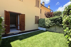 Une maison avec une pelouse bien entretenue, des volets en bois aux fenêtres et un petit hall d’entrée.