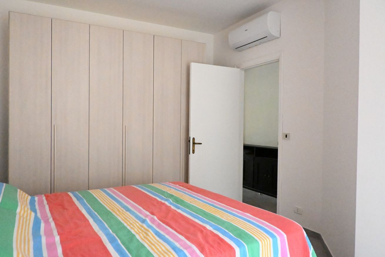 A bedroom with a bed, a wardrobe, and an air conditioning unit.