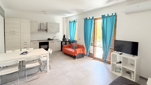 A compact living space with a kitchenette, a dining area, a sofa, and a TV. - N305 – Numana, comfortable three-room apartment with garden (Numana)