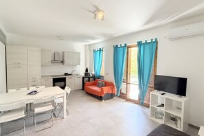 A compact living space with a kitchenette, a dining area, a sofa, and a TV. - N305 – Numana, comfortable three-room apartment with garden (Numana)