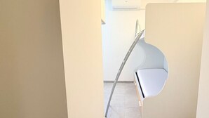 A modern interior with a white chair, a metal ladder, and a tiled floor. - N305 – Numana, comfortable three-room apartment with garden (Numana)