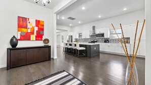 Une cuisine moderne avec des meubles blancs, un îlot central et un coin repas avec des chaises blanches.