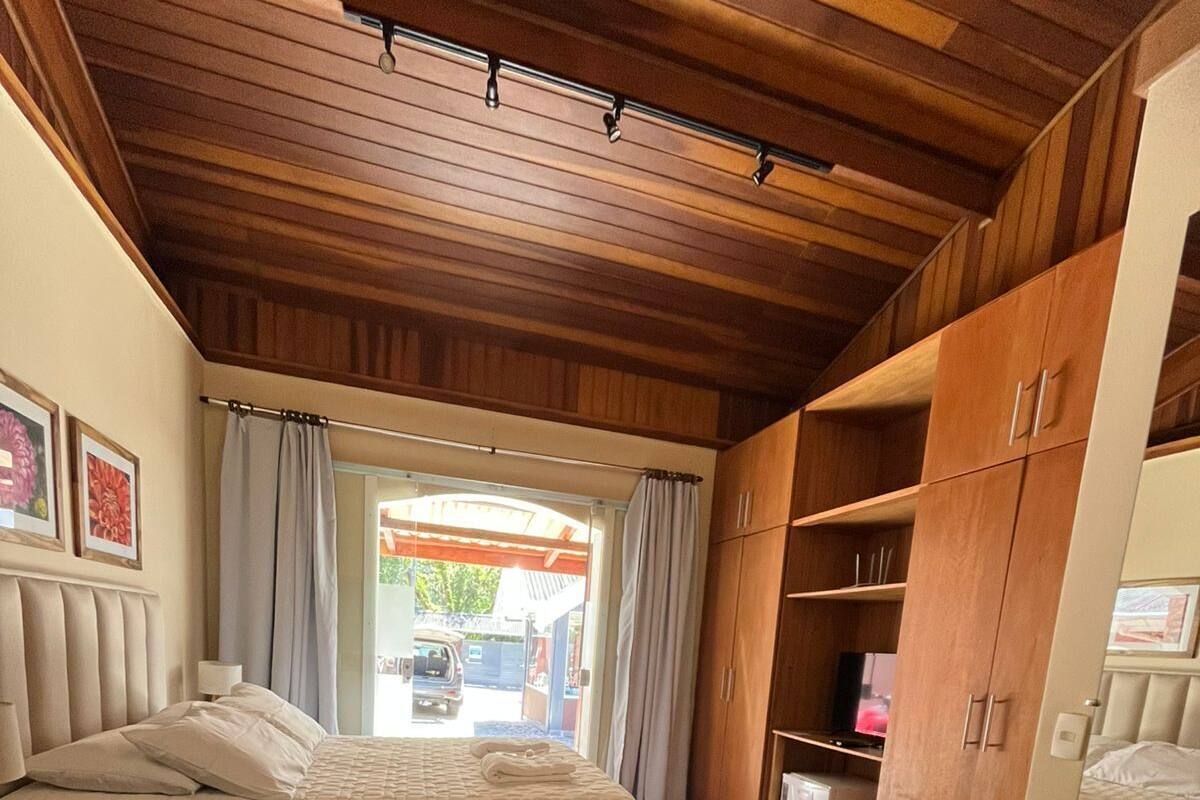 Ein Schlafzimmer mit Bett, Schrank, Heizkörper und Blick ins Freie.
