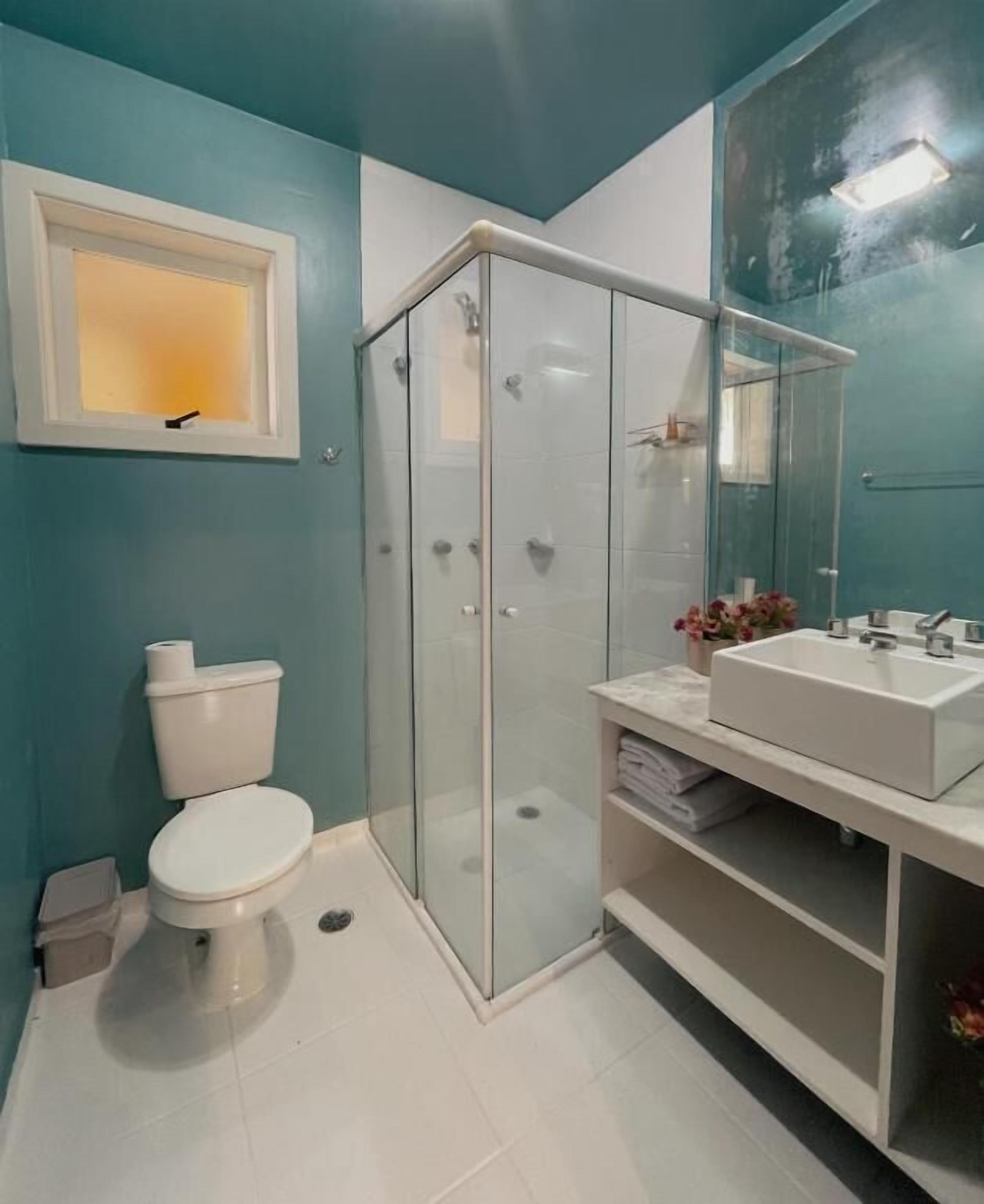 Un baño con cabina de ducha de vidrio, inodoro blanco y lavabo con espejo.
