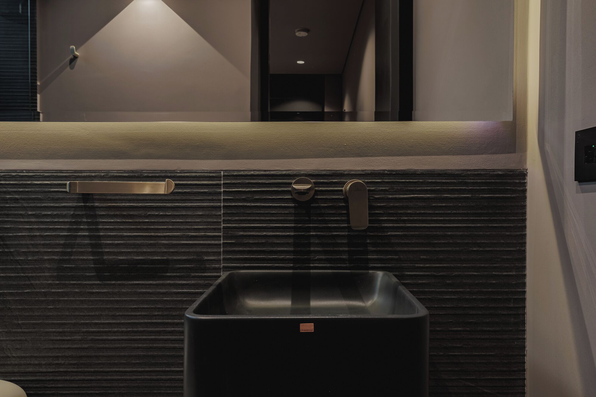 Ein modernes Badezimmer mit einem schwarzen Waschbecken, einem Handtuchhalter und einem Spiegel darüber.