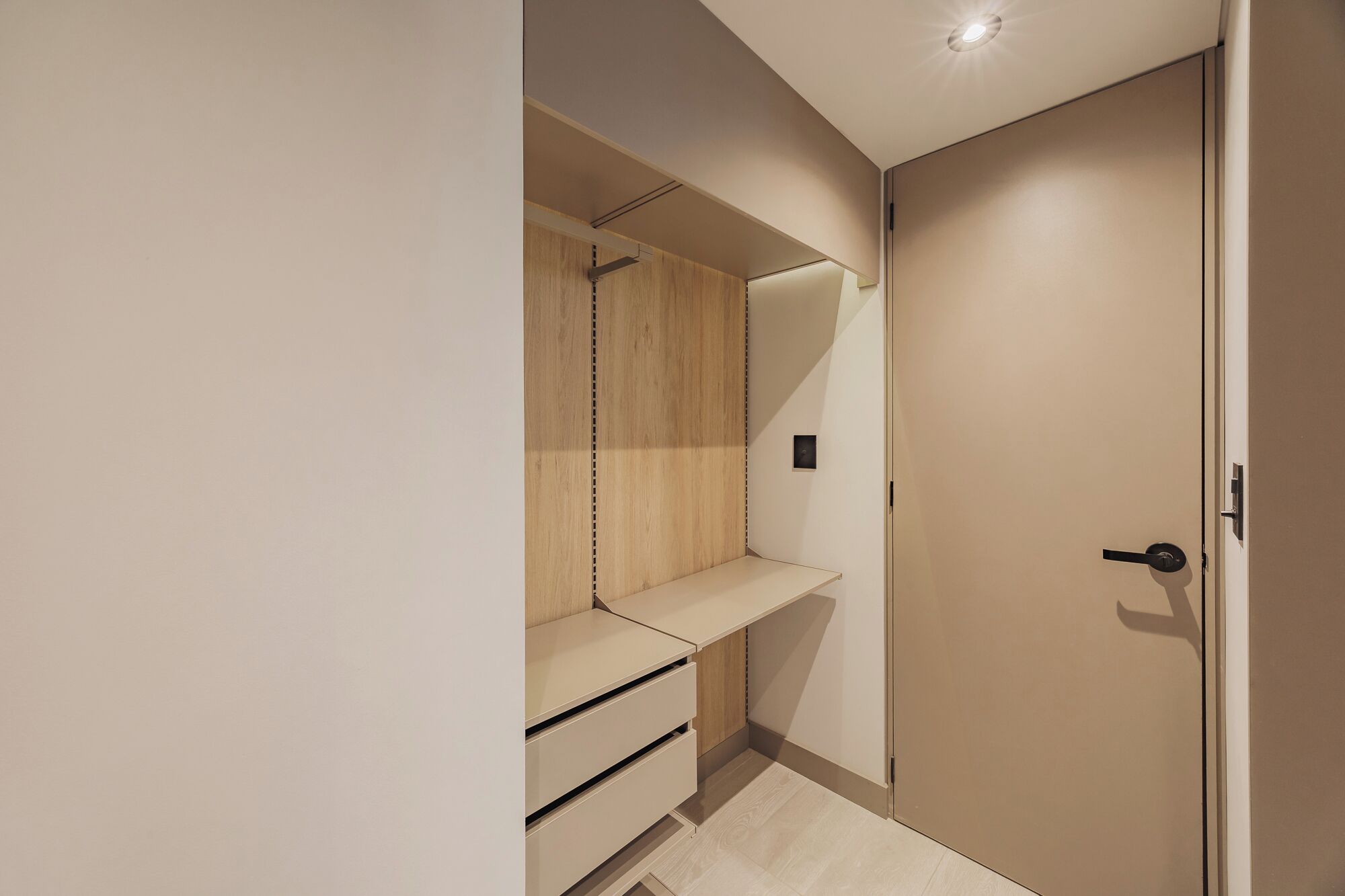 A walk-in closet with a wooden wardrobe, a hanging rod, and a shelf.