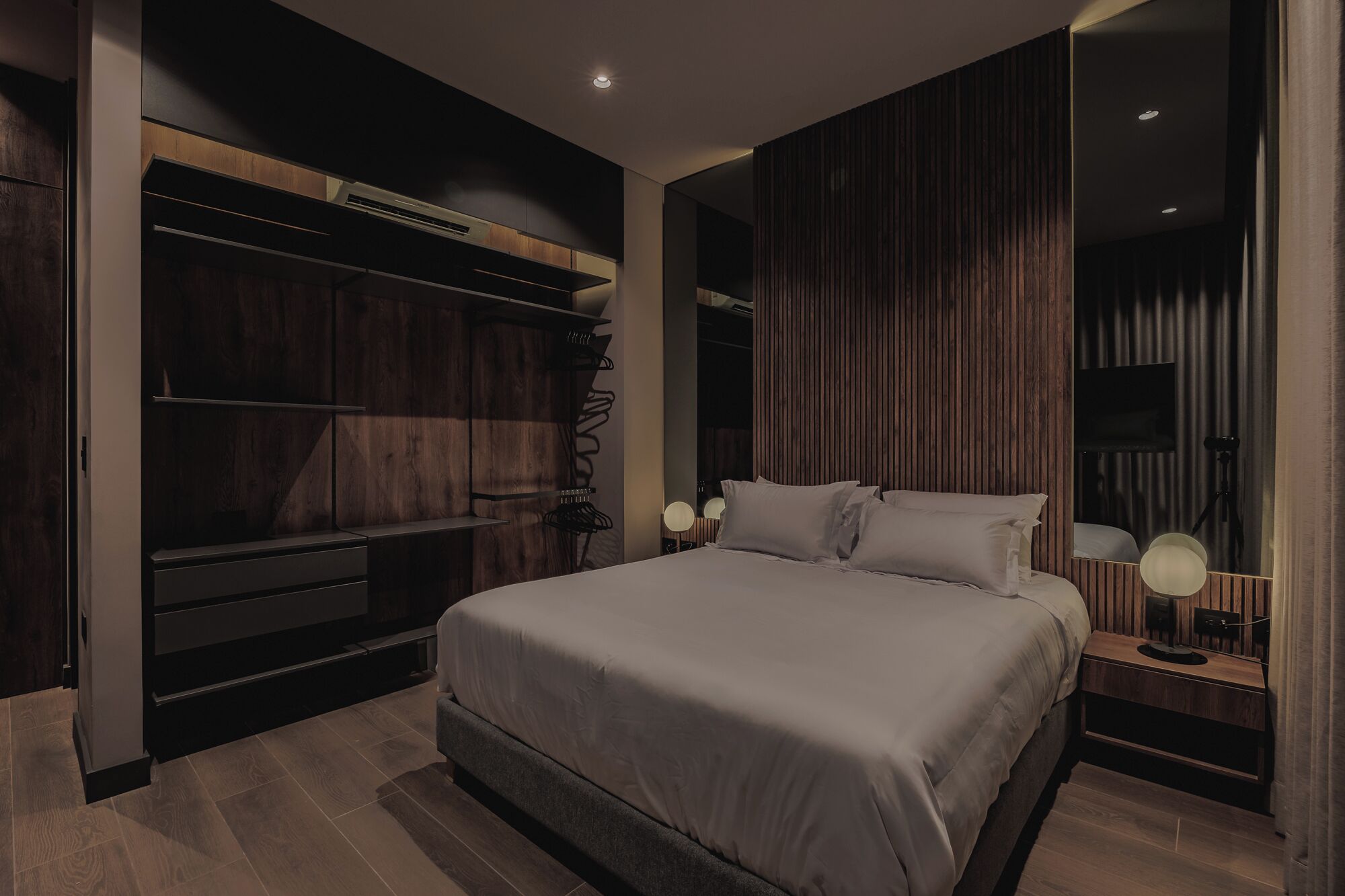 A modern bedroom with a large bed, built-in wardrobe, and a television.