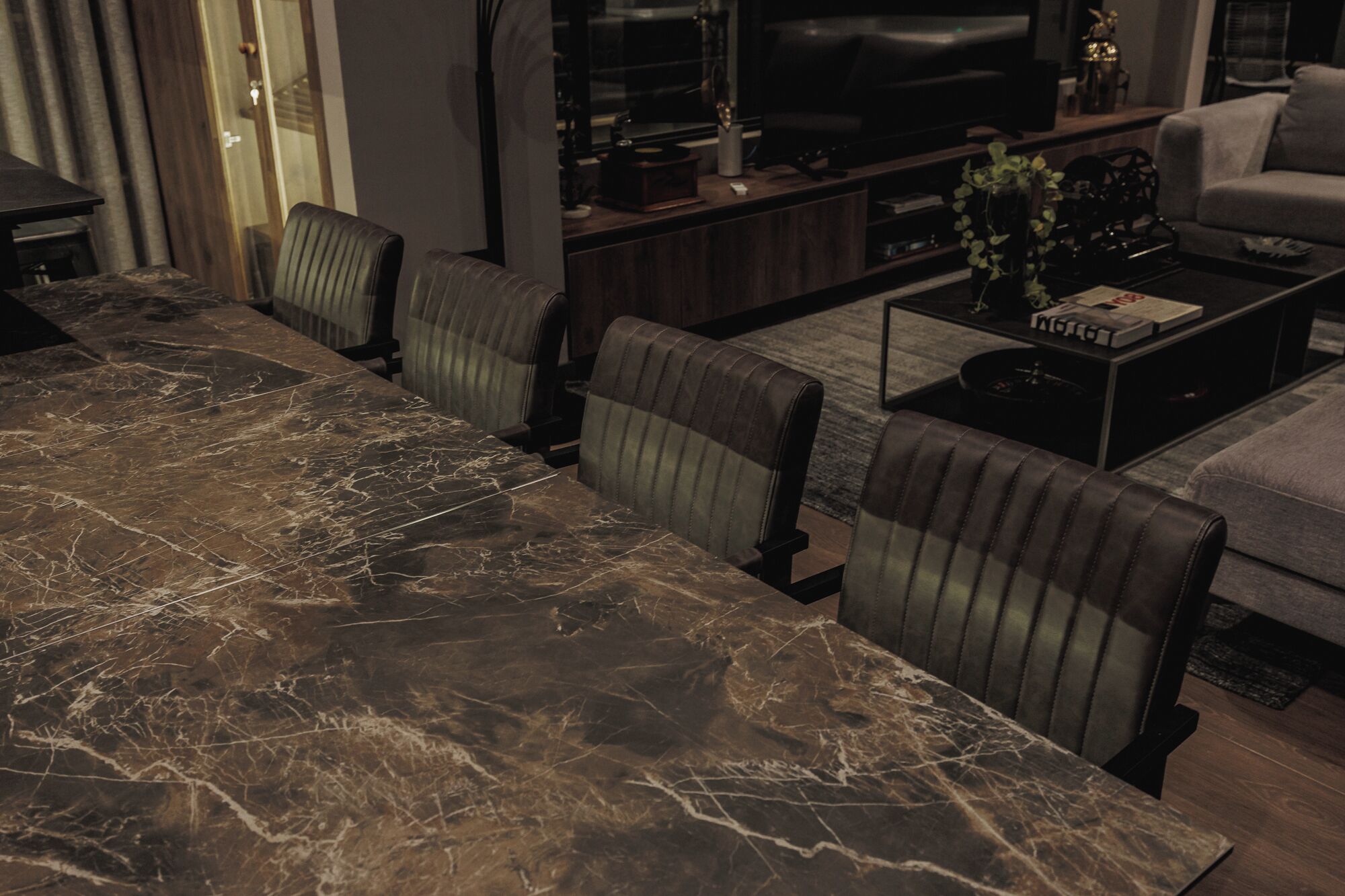 Un salon moderne avec une table à manger en marbre, des fauteuils en cuir, un canapé et une table basse.