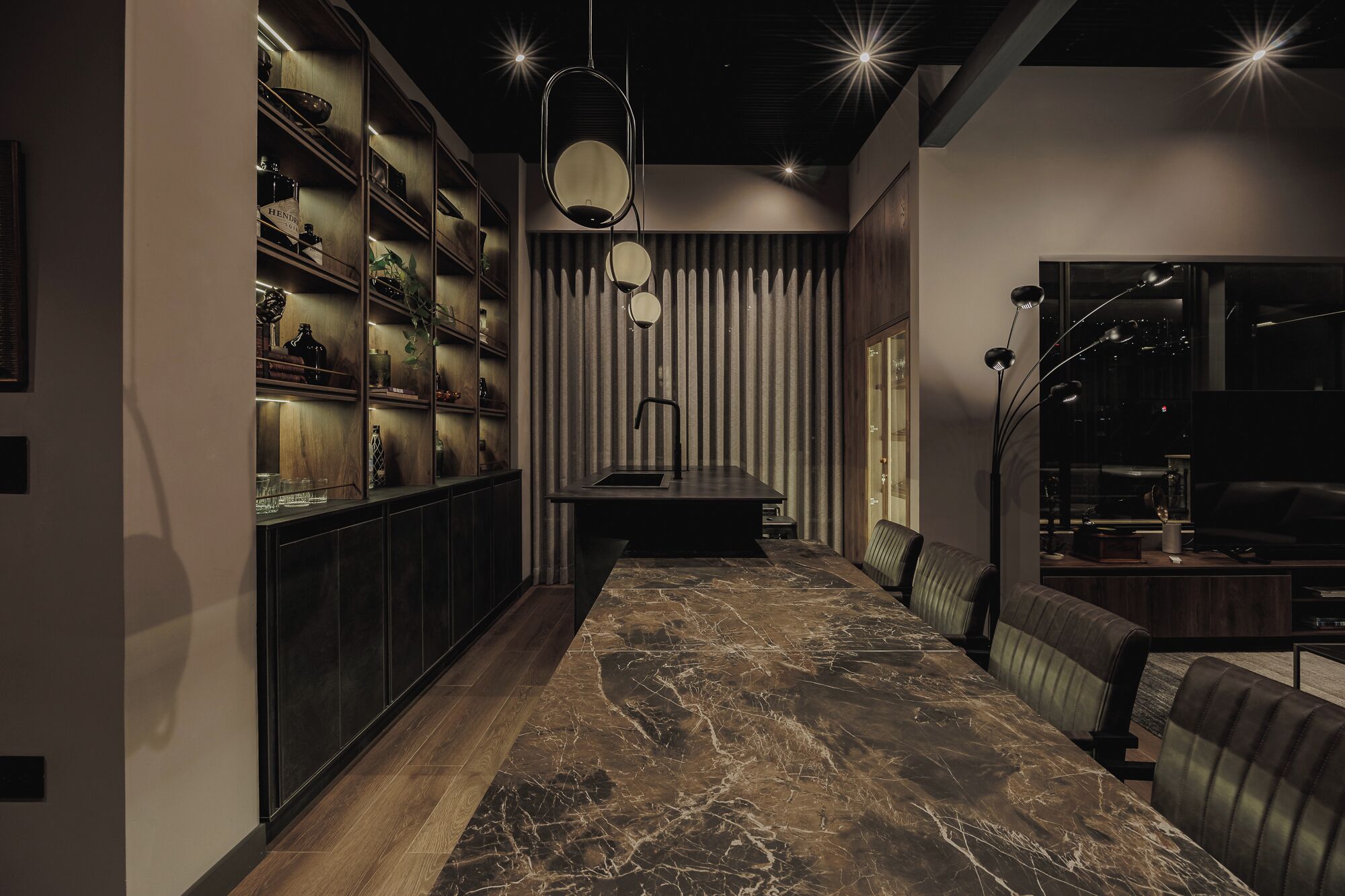 Un interior moderno con una estantería de madera oscura, suelo de baldosas de mármol y una zona de estar con sofá de cuero y una mesa.